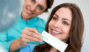 Rolling Hills Dental Patient smiles while holding up a shade chart to see how light she wants to whiten her teeth